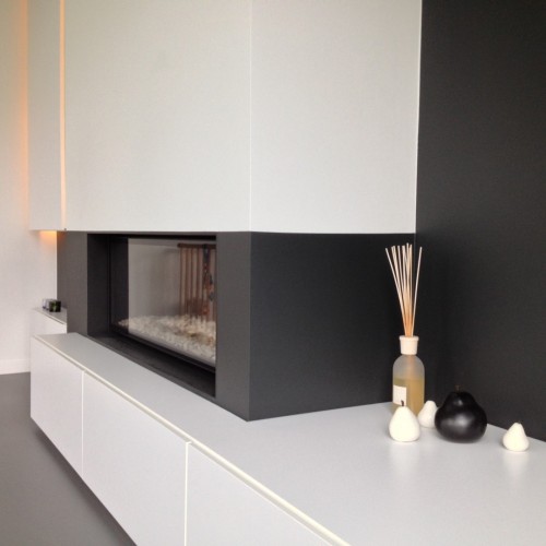 In deze woning creëerden we een laag TV-meubel rondom de haard waarin tal van toestellen verstopt werden. Verder adviseerden we de bewoners om de muur in een donkere tint te verven, zodat het TV-meubel nog meer tot zijn recht komt én om een intieme sfeer te creëren. Kast-ID Antwerpen